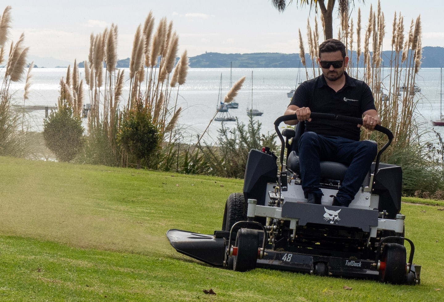 Person operating Bobcat mower by the sea