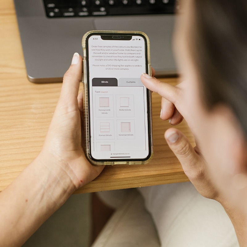 Person scrolling Bargain Blinds website on their phone